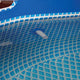 Close-up of a blue pool cover with a grid pattern and a white drain plug.