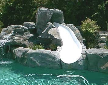 Rocky water slide in a pool with trees in the background